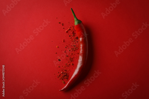 Bilde på lerret Tasty chilli pepper and powder spice on red background