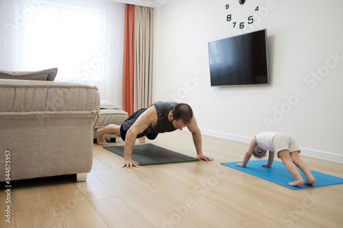 Young man with his son doing yoga at home on quarantine. .