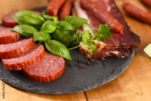 Ham and smoked sausage cutting on a slate plate. A snack in between.