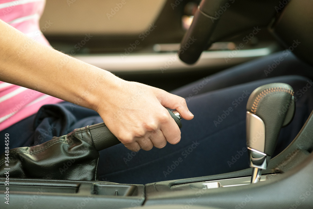 Close up of female driver hand holding hand brake in a car. Close up of female driver hand holding hand brake in a car.