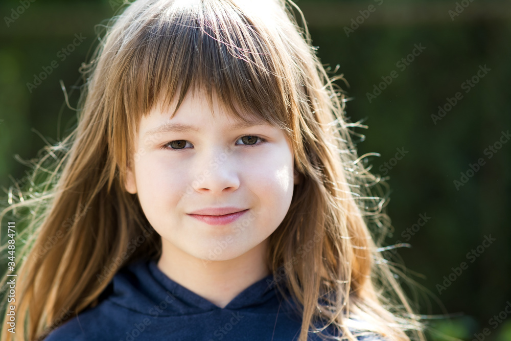 Portrait of pretty child girl with gray eyes and long fair hair smiling outdoors on blurred bright background. Cute female kid on warm summer day outside. Portrait of pretty child girl with gray eyes and long fair hair smiling outdoors on blurred bright background. Cute female kid on warm summer day outside.