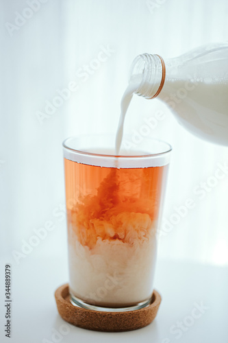 pouring milk into a black tea glass