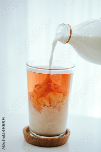 pouring milk into a black tea glass
