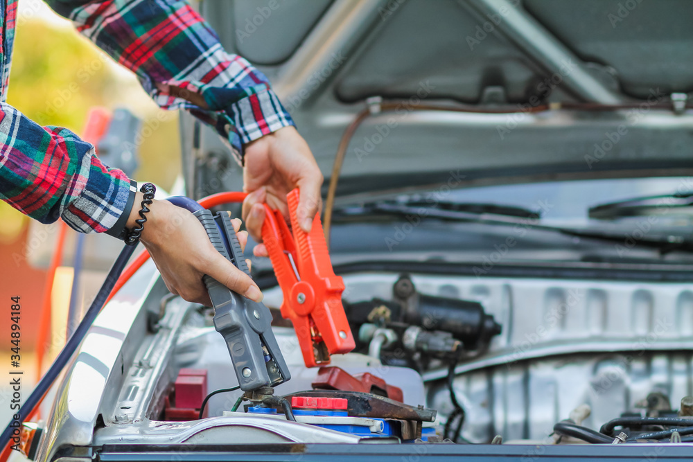 A woman holding a black and red Jumper cable that shows the positive