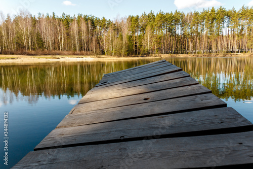 wooden bridge on the lake above the water against the background of the forest