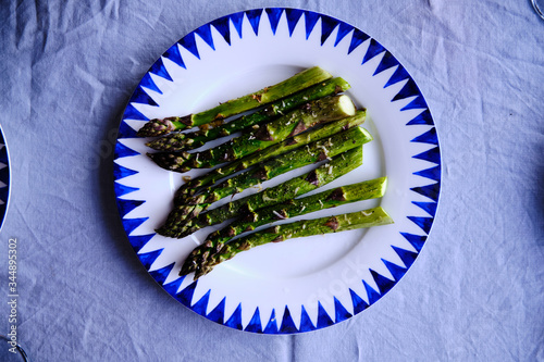 Baked asparagus on baking sheet with seasoning and olive oil