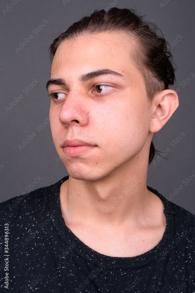 Face of young handsome man with hair tied looking away