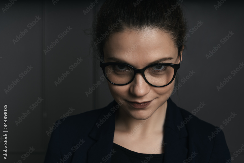Portrait of a beautiful young business woman standing against black wall