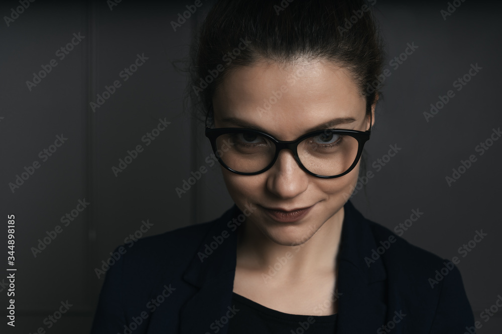 Portrait of a beautiful young business woman standing against black wall Portrait of a beautiful young business woman standing against black wall