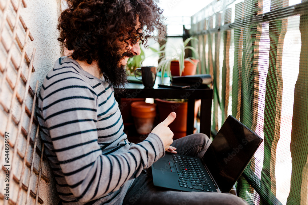 Young afro caucasian with laptop in his balcony Young afro caucasian with laptop in his balcony