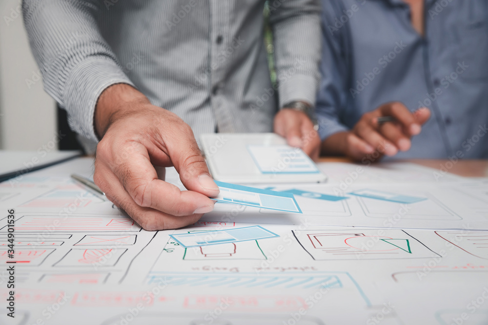 UX or UI designers designing on their smartphone application layout prototype project. UX or UI designers designing on their smartphone application layout prototype project.