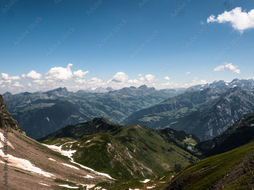 Snow covered mountain peaks and fields near Engelberg in Switzerland during a sunny beautiful summer hike