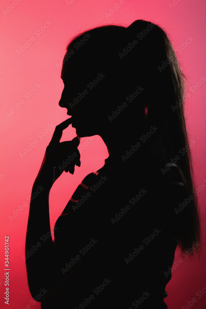 silhouette of thoughtful girl on red lightened background, unrecognizable woman profile with long hair ponytail, concept female beauty, seduction