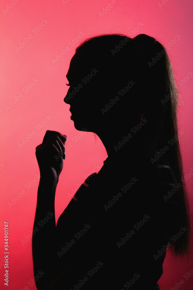 silhouette of confused girl on red lightened background, unrecognizable woman face profile, concept emotions, stress
