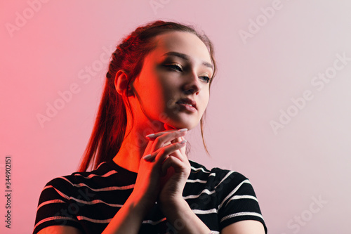 portrait of a beautiful sensual girl with makeup and long hair on studio red background, concept beauty and fashion