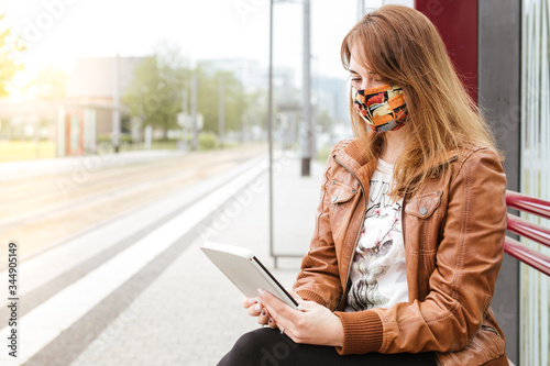 Frau wartet an Haltestelle mit Reader photo