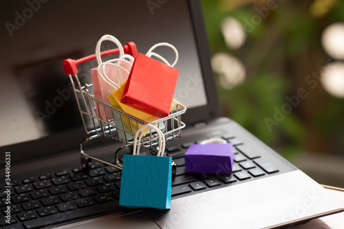 Paper shopping bags in a trolley or shopping cart on keyboard. Concept about online shopping that customers can buy everything from home or office and the messenger will deliver to the doorstep.