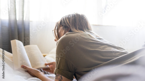Woman engrossed reading a book at home on the bed in the daytime