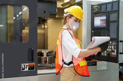 A woman supervisor/operator in a factory is checking on a terminal of milling machine.