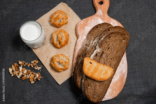 Baking, dark bread, cookies and rolls on a dark background.
Kraft paper. Milk in a transparent glass.