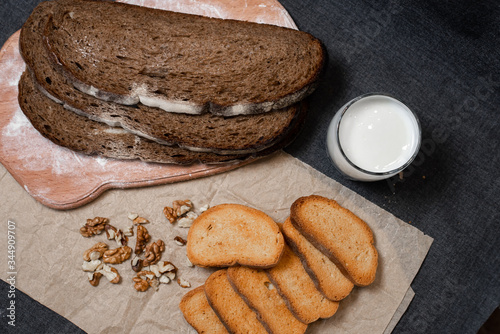 Baking, dark bread, cookies and rolls on a dark background.
Kraft paper. Milk in a transparent glass.