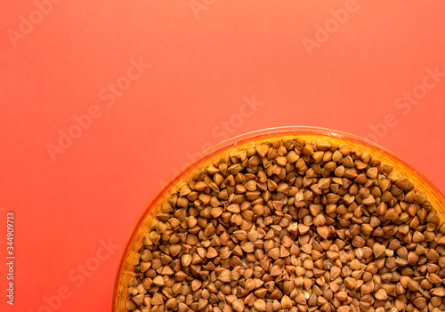 uncooked buckwheat in a container on a red background in the corner photo