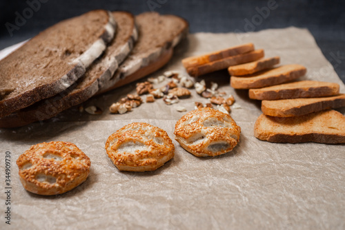 Baking, dark bread, cookies and rolls on a dark background.
Kraft paper. Milk in a transparent glass.