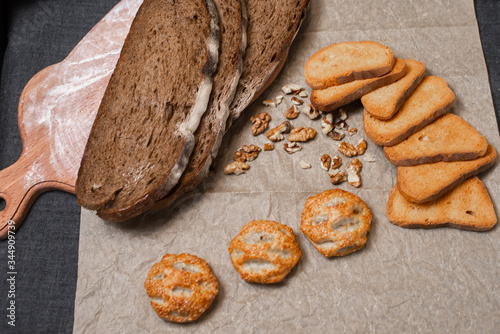 Baking, dark bread, cookies and rolls on a dark background.
Kraft paper. Milk in a transparent glass.