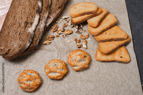 Baking, dark bread, cookies and rolls on a dark background.
Kraft paper. Milk in a transparent glass.