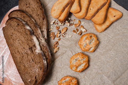 Baking, dark bread, cookies and rolls on a dark background.
Kraft paper. Milk in a transparent glass.