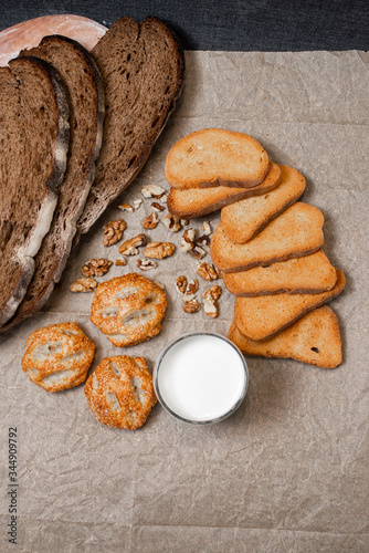 Baking, dark bread, cookies and rolls on a dark background.
Kraft paper. Milk in a transparent glass.
