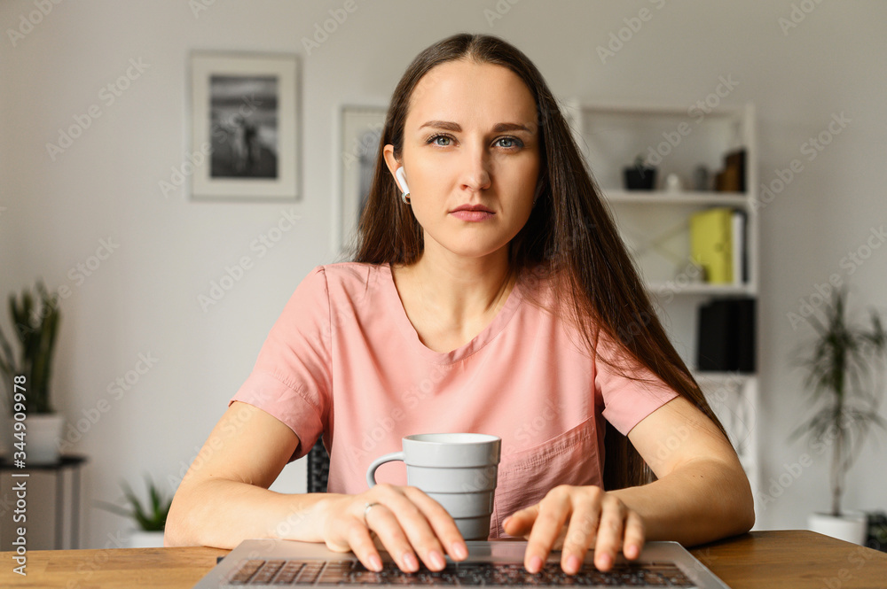 Webcam view of concentrated young attractive girl in casual wear at home,  she typing on the keyboard with a serious face and watching intently on the  screen. Front view Photos | Adobe