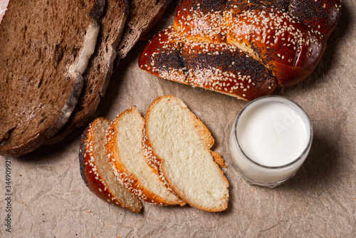 Baking, dark bread, cookies and rolls on a dark background.
Kraft paper. Milk in a transparent glass.