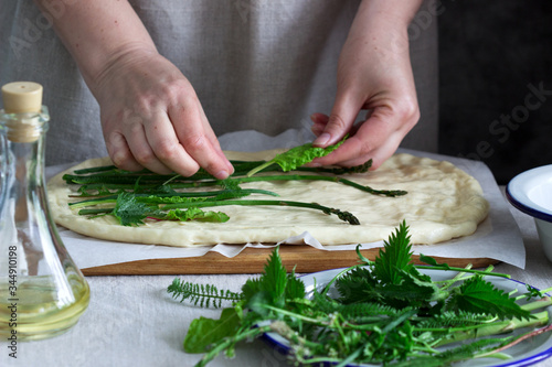 Woman makes focaccia from yeast dough with various herbs. Rustic style. photo