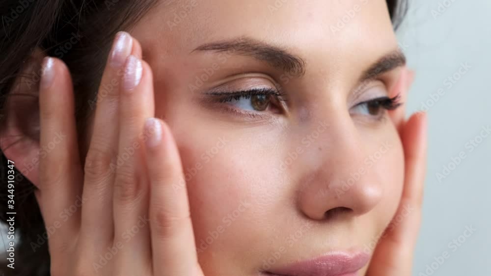 Young woman happy attractive woman apply skin care cream on face. Girl inflicts moisturizing lifting facial cream, healthy skin care treatment concept. Facial massage with glass jars. Young woman happy attractive woman apply skin care cream on face. Girl inflicts moisturizing lifting facial cream, healthy skin care treatment concept. Facial massage with glass jars.