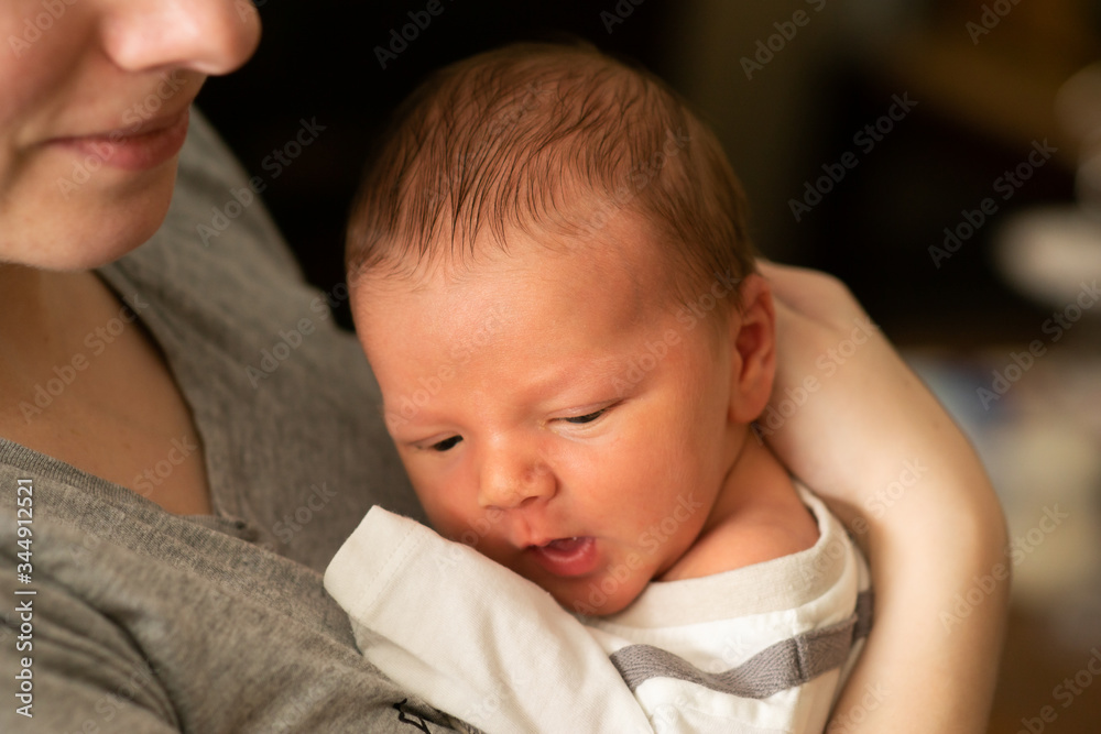 Tiny caucasian newborn baby boy resting in mothers arms after breastfeeding session. Baby with yellow skin because of baby jaundice, typical condition for first days of newborns life. Tiny caucasian newborn baby boy resting in mothers arms after breastfeeding session. Baby with yellow skin because of baby jaundice, typical condition for first days of newborns life.