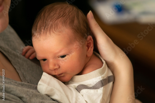 Obraz na płótnie Tiny caucasian newborn baby boy resting in mothers arms after breastfeeding session. Baby with yellow skin because of baby jaundice, typical condition for first days of newborns life. w salonie