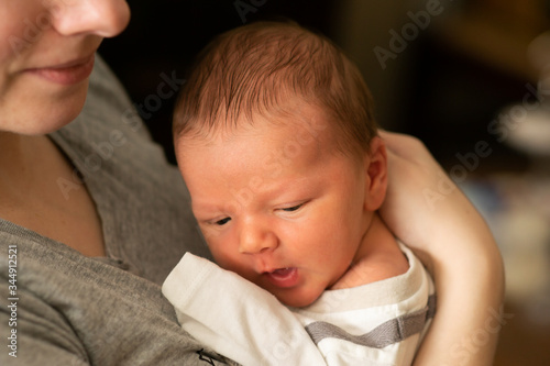 Obraz na płótnie Tiny caucasian newborn baby boy resting in mothers arms after breastfeeding session. Baby with yellow skin because of baby jaundice, typical condition for first days of newborns life. w salonie