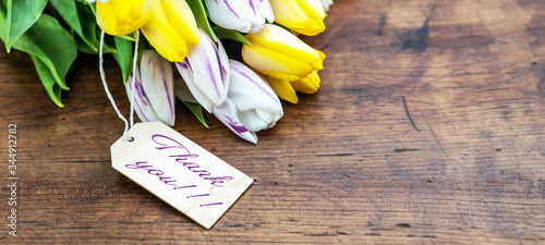 Thank you background banner - Bunch Bouquet of colorful tulips and wooden label on dark rustic wooden table, with space for text
