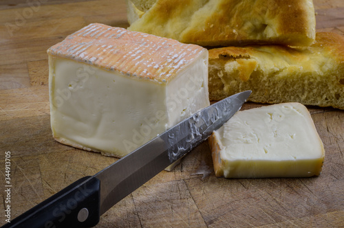 Tableau sur toile Piece of sliced taleggio italian cheese with focaccia bread on a wooden cutting board with knife close up