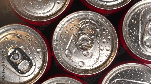 A lot of red metal cans roatate. Droplets of water on bottles. Nice cinematic footage. The concept of a production or can factory.