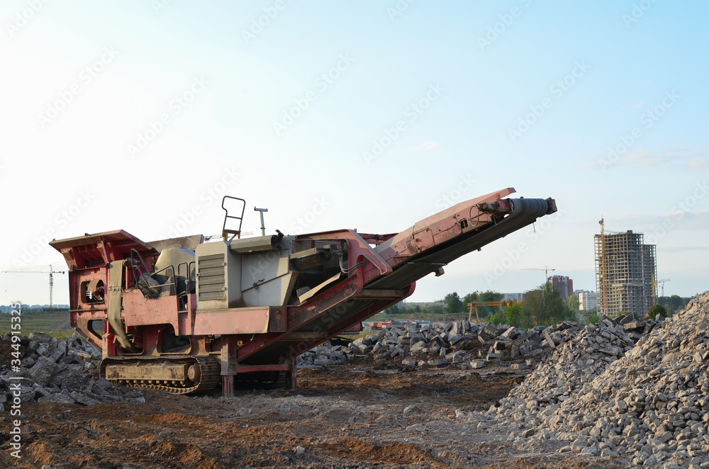 Obraz premium Mobile Stone Jaw crusher machine for crushing concrete into gravel and subsequent cement production. Salvaging and recycling of the demolition construction waste on landfill. Reuse concrete.
