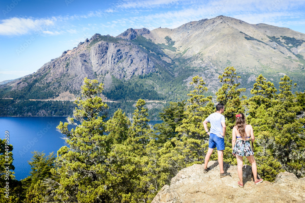 People in a mountain landscape in sunny day. Green pines and lake under the mountain in Bariloche.