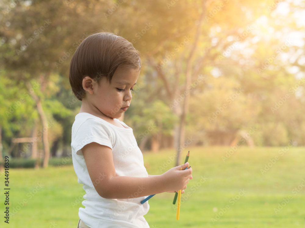 Cute little toddler boy holding color pencils in the park. Cute little toddler boy holding color pencils in the park.