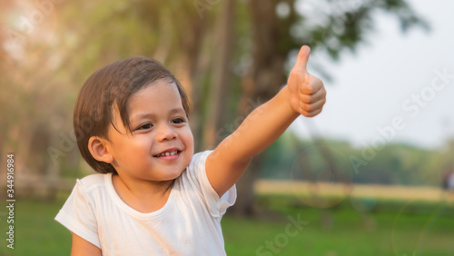 Cute little boy giving thumbs up with smiling face.