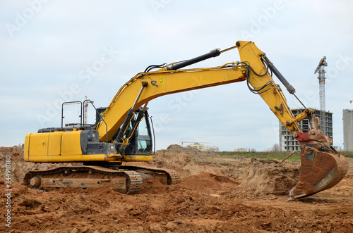 Wallpaper Mural Excavator with a large iron bucket on a construction site during road works. Backhoe dig the ground for the foundation, laying storm sewer pipes. Installation of water main systems. Torontodigital.ca
