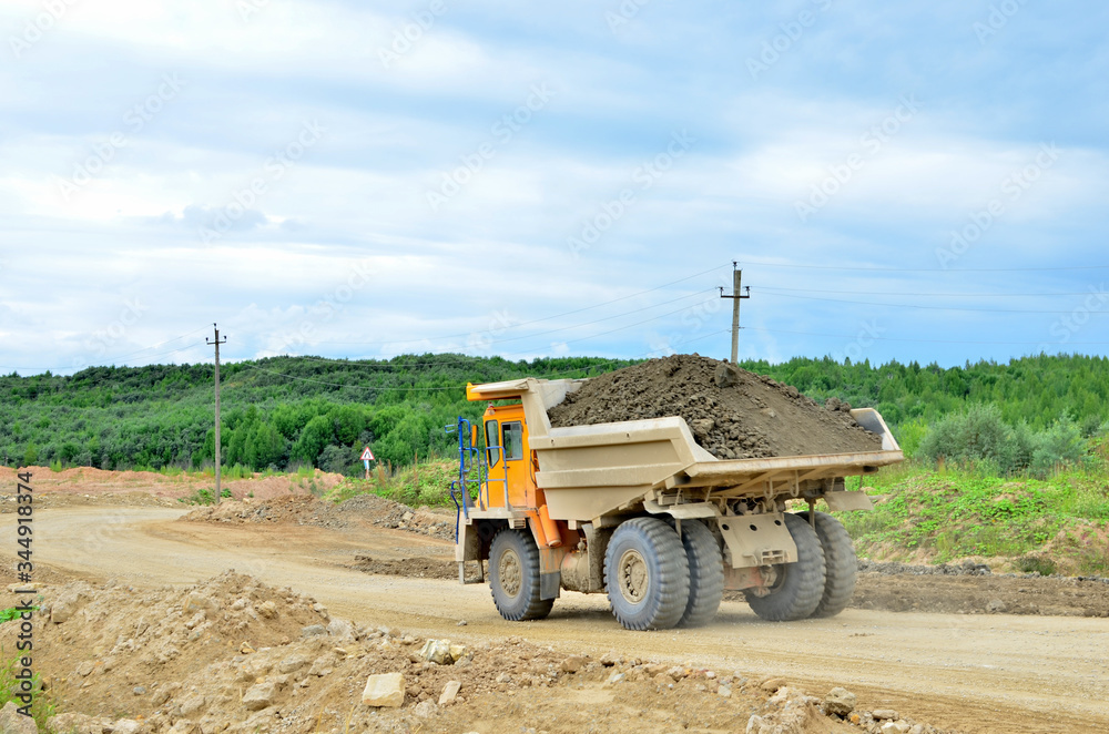 Obraz premium Big mining truck transport of minerals in the quarry. Open-cast mining of extracting rock or minerals from the earth. Largest dolomite deposit open-pit mining Gralevo, Belarus, Vitebsk region