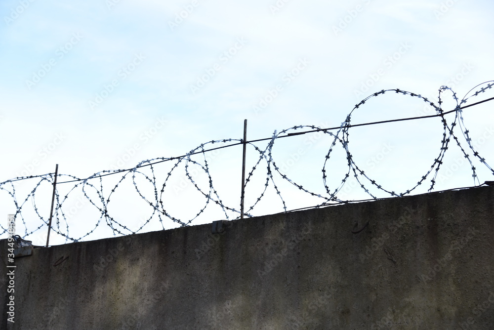 Fence with barbed wire against a blue sky background. Security concept, forbidden territory, entry prohibited/no entry Fence with barbed wire against a blue sky background. Security concept, forbidden territory, entry prohibited/no entry