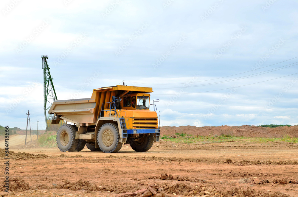 Big yellow mining truck working in the limestone open-pit. Loading and transportation of minerals in the dolomite mining quarry. Belarus, Vitebsk, in the largest dolomite deposit, quarry Big yellow mining truck working in the limestone open-pit. Loading and transportation of minerals in the dolomite mining quarry. Belarus, Vitebsk, in the largest dolomite deposit, quarry