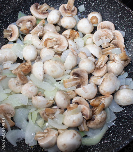Mushrooms with onions in a frying pan. Preparing lunch and dinner.